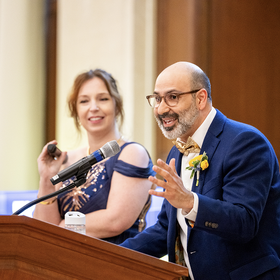 Two people smiling and presenting at a lectern.